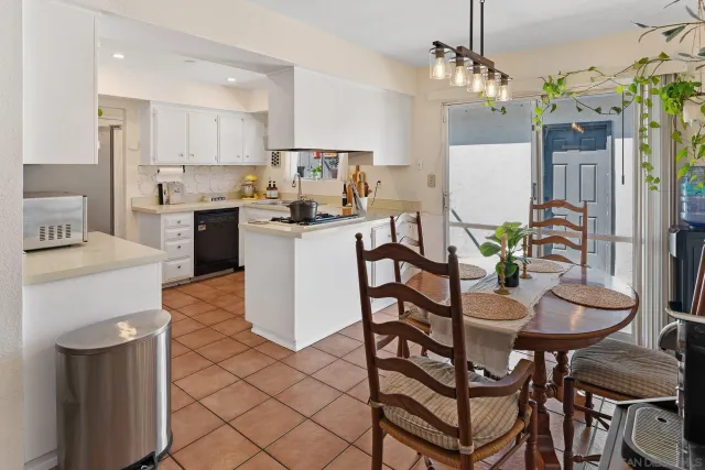 a kitchen with stainless steel appliances kitchen island granite countertop a dining table chairs and white cabinets
