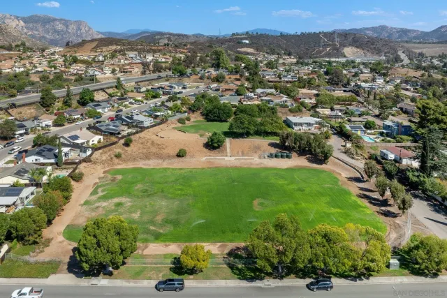 an aerial view of residential houses with outdoor space and trees