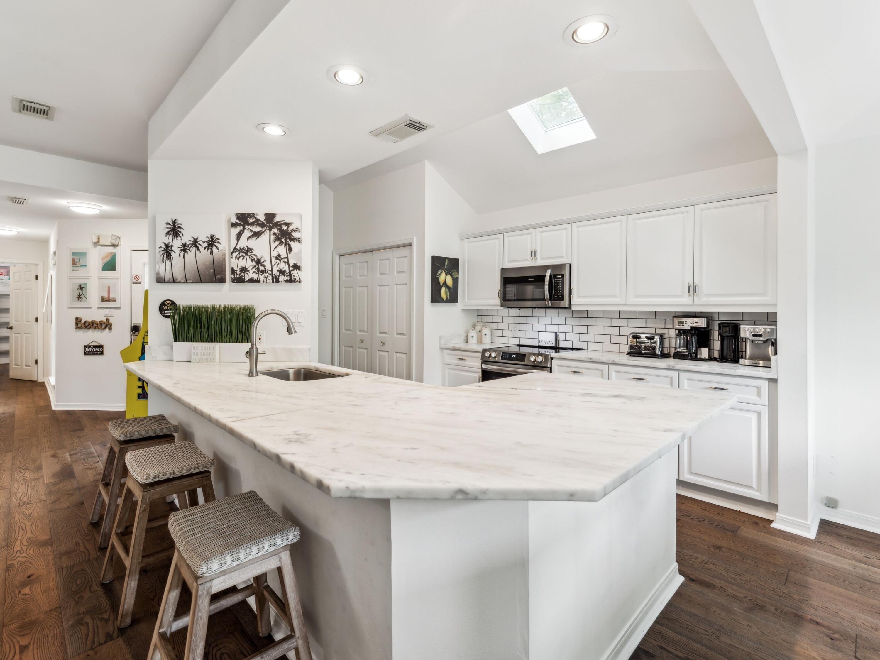 8855 Baypine Drive Miramar Beach, FL 32550 - Photo 10 of 49 a kitchen with stainless steel appliances kitchen island granite countertop a stove a sink a refrigerator a microwave oven with white cabinets and wooden floor