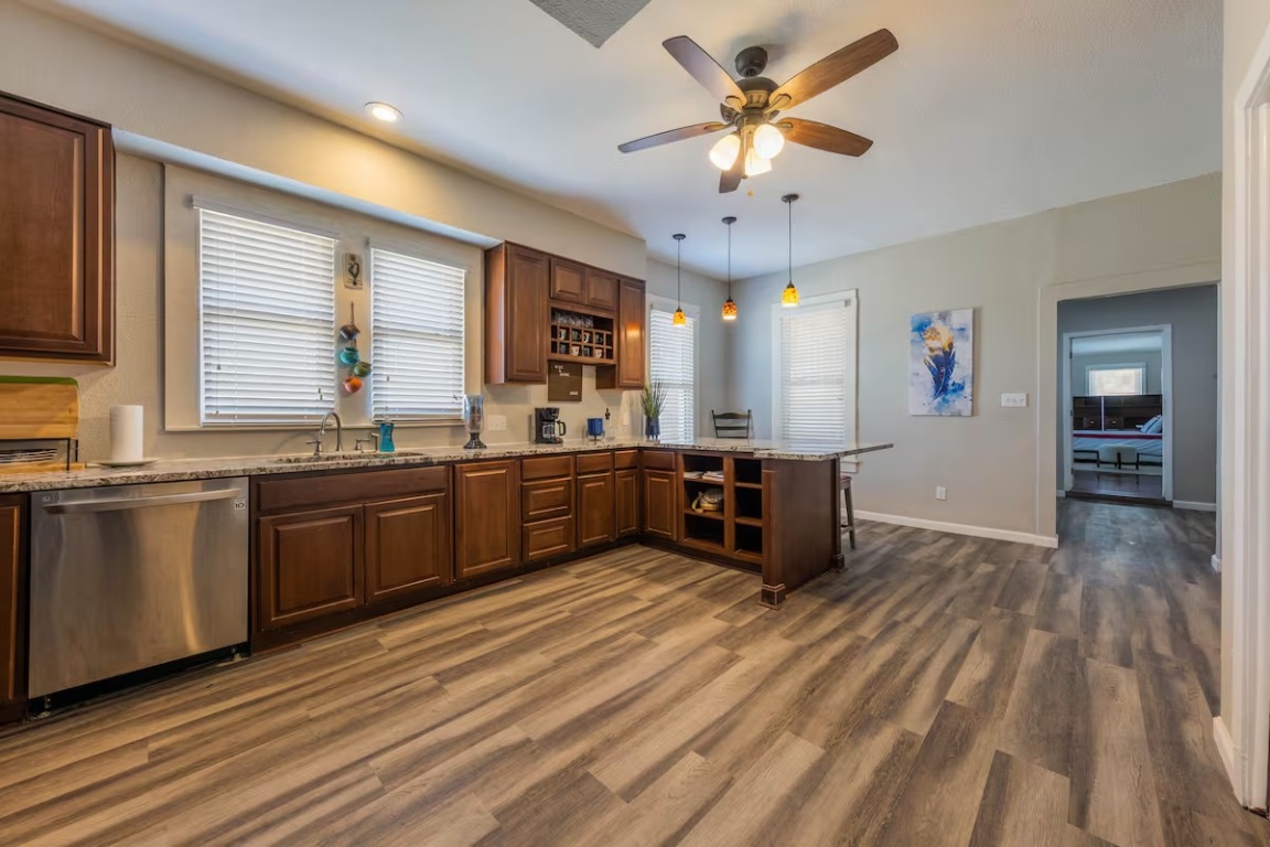 1212 North Main Street Elgin, TX 78621 - Photo 8 of 31 Kitchen featuring a peninsula, dishwasher, light stone countertops, and healthy amount of natural light