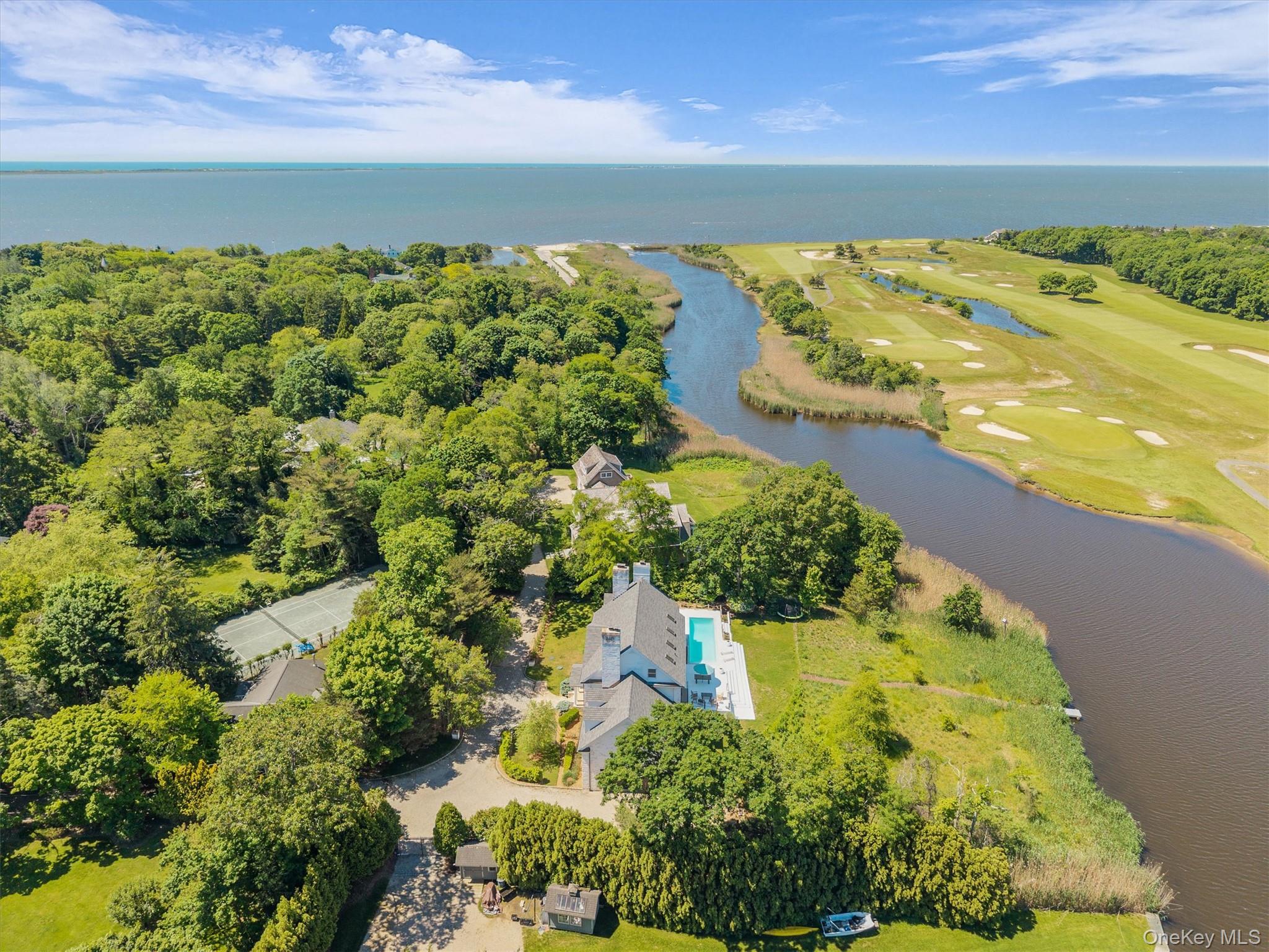 68 South Howells Point Road Bellport, NY 11713 - Photo 3 of 47 Waterfront property featuring a white multi-story residence with a pool, expansive lawn, and a private dock. Views of golf course and Great South Bay