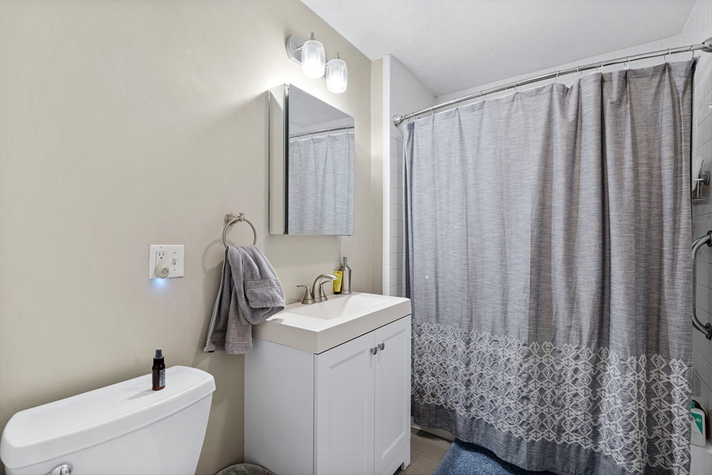 79 Saxton Street, Unit 3 Boston, MA 02125 - Photo 6 of 12 a bathroom with a toilet a sink and curtain