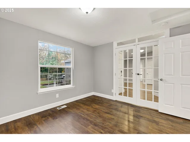 an empty room with wooden floor and windows