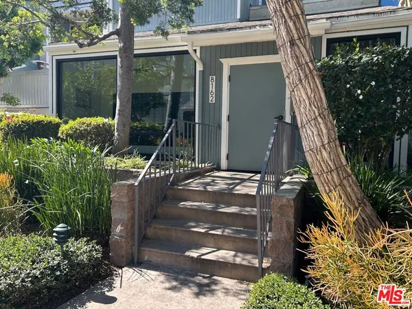 a front view of a house with a tree