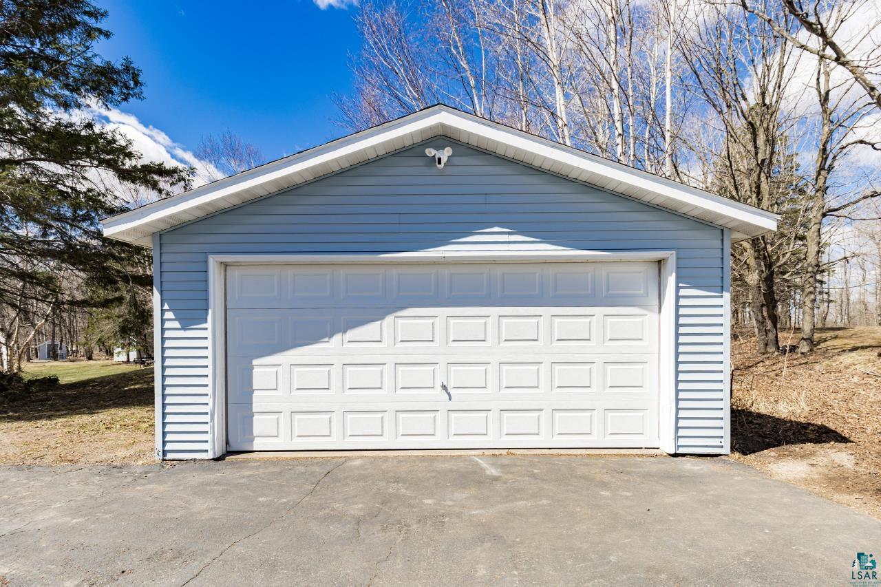 3645 Haines Road Hermantown, MN 55811 - Photo 16 of 35 Attached garage with light blue vinyl siding and a white paneled garage door