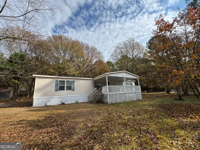 a front view of house with yard and trees in the background