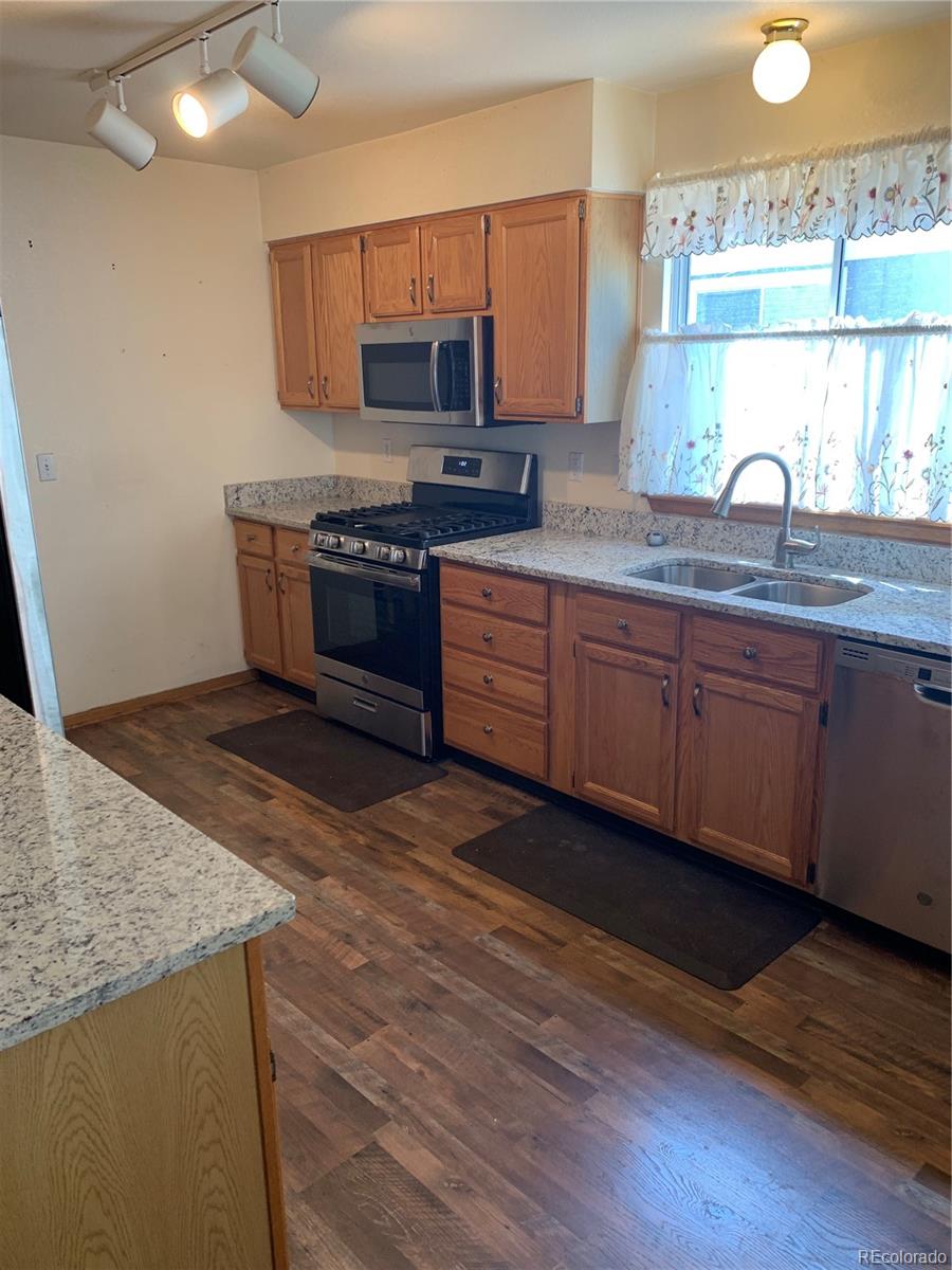 1187 West 133rd Way Westminster, CO 80234 - Photo 4 of 10 a kitchen with stainless steel appliances granite countertop a stove a sink and a microwave