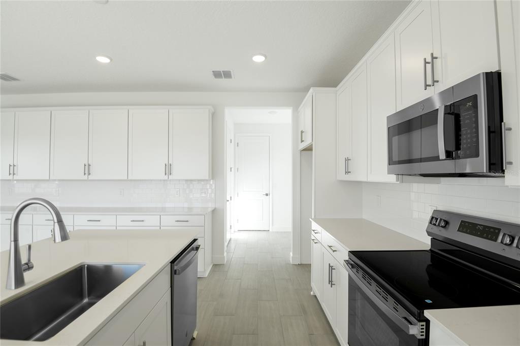 153 Waterstone Loop Tavares, FL 32778 - Photo 7 of 22 a kitchen with stainless steel appliances a sink a stove cabinets and a counter top space