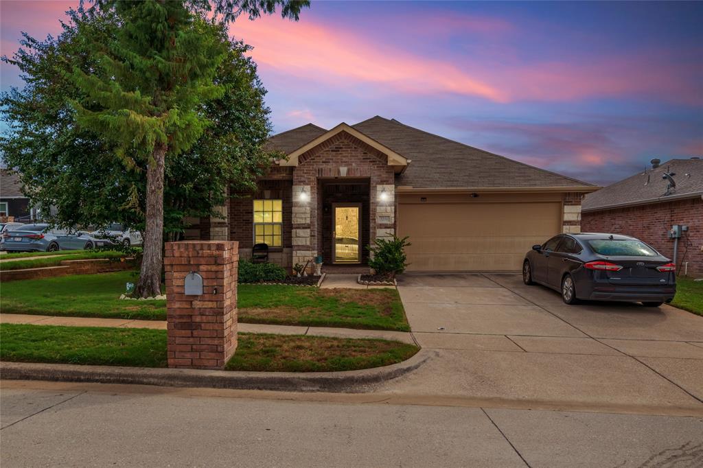 View of front of property with brick siding, concrete driveway, a garage, and a front yard