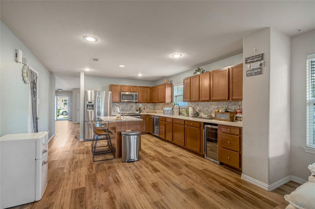 3216 Jetranger Road Fort Worth, TX 76053 - Photo 12 of 35 Kitchen featuring a kitchen breakfast bar, tasteful backsplash, brown cabinets, light wood-type flooring, and recessed lighting
