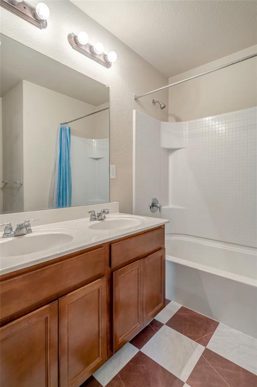 3216 Jetranger Road Fort Worth, TX 76053 - Photo 23 of 35 Bathroom with shower / bath combination with curtain, double vanity, dark tile patterned flooring, and a textured ceiling