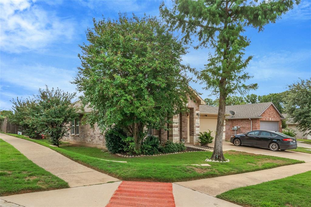 3216 Jetranger Road Fort Worth, TX 76053 - Photo 5 of 35 View of property hidden behind natural elements featuring a front lawn, brick siding, concrete driveway, and a garage