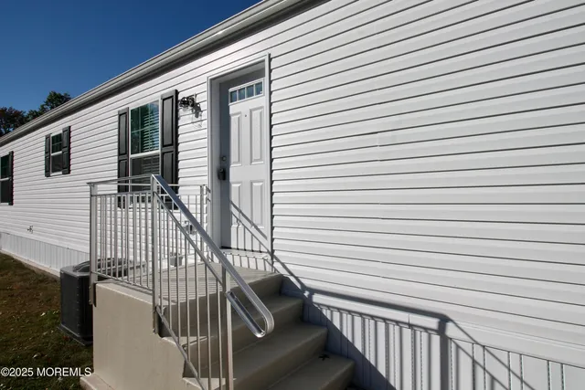 a view of an empty room with wooden floor and a kitchen