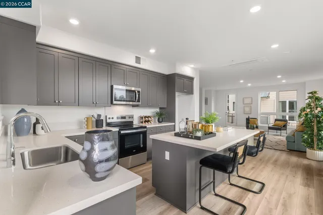 a kitchen with a sink dishwasher a stove a kitchen island with chairs and wooden floor