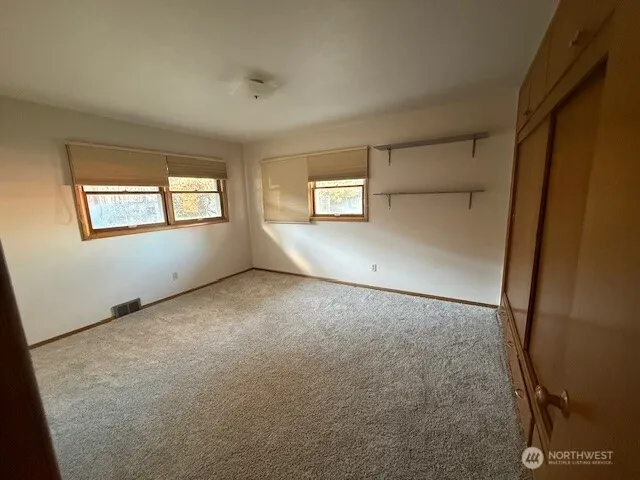 an empty room with windows and closet