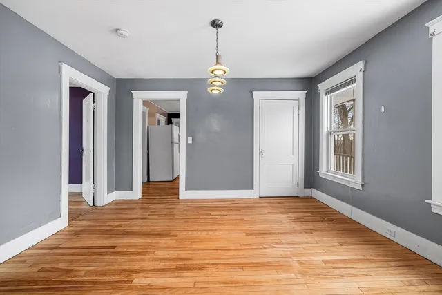 a view of an empty room with wooden floor and windows