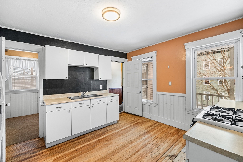 748 Water Street Fitchburg, MA 01420 - Photo 26 of 39 a kitchen with a stove oven and white cabinets with wooden floor