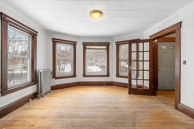 a view of an empty room with glass door and wooden floor