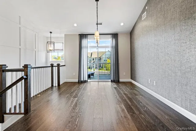 a open kitchen view with stainless steel appliances granite countertop a stove top oven a refrigerator and a dining table with wooden floor