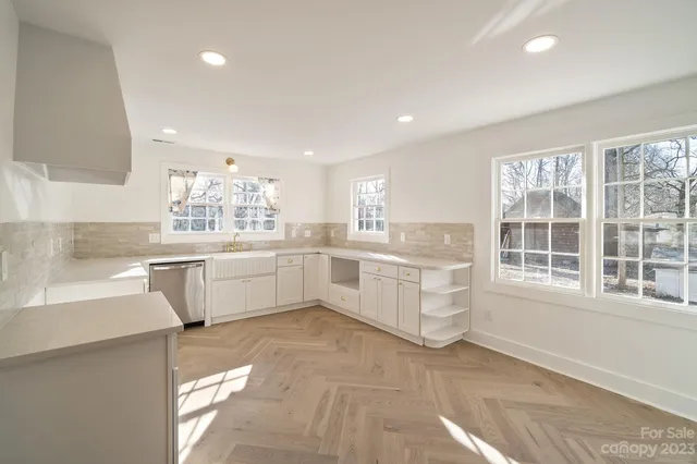a large white kitchen with cabinets and a window