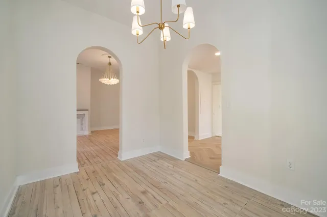 an empty room with wooden floor chandelier fan and windows