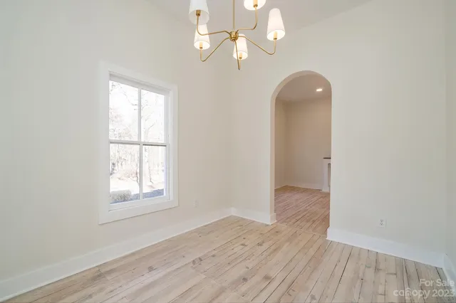 a view of an empty room with wooden floor and a ceiling fan