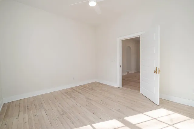 a view of empty room with wooden floor and fan