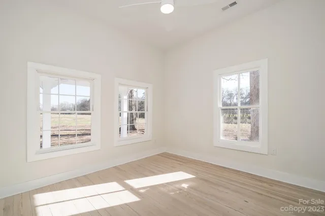an empty room with wooden floor and windows