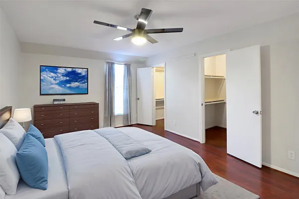a view of an empty room with wooden floor and a ceiling fan