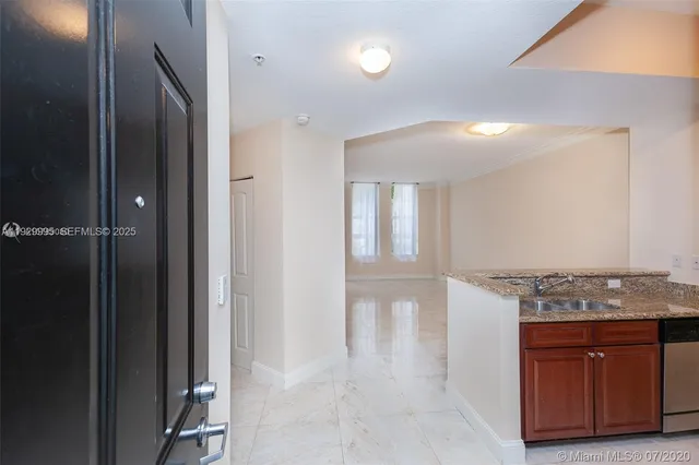 a view of kitchen with granite countertop cabinets and refrigerator
