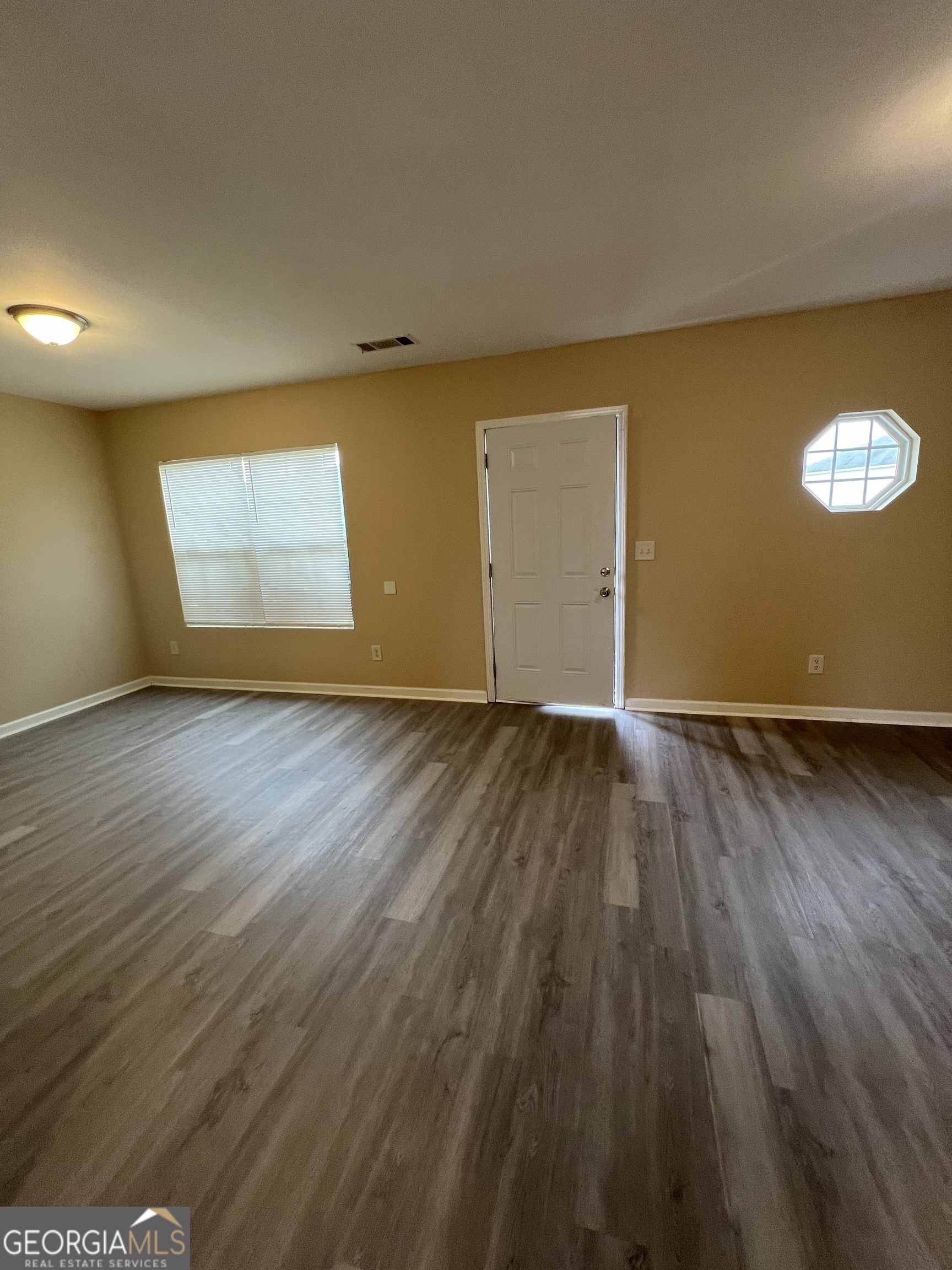 733 Wheel House Lane Monroe, GA 30655 - Photo 2 of 7 an empty room with wooden floor and windows