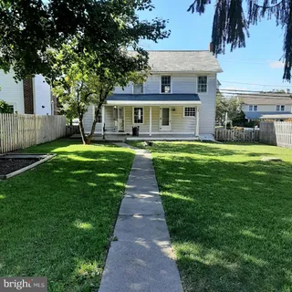 a front view of a house with a garden and trees