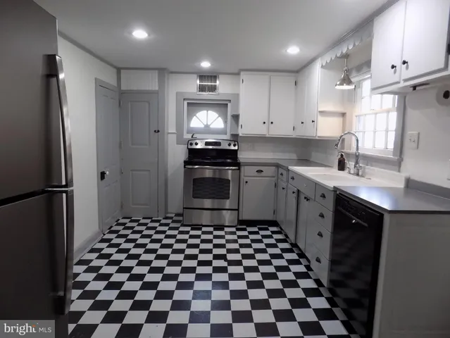 a kitchen with a checkered floor and white cabinets