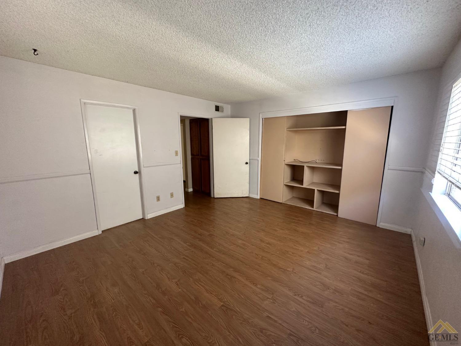Undisclosed Address Bakersfield, CA 93313 - Photo 13 of 30 an empty room with wooden floor and closet