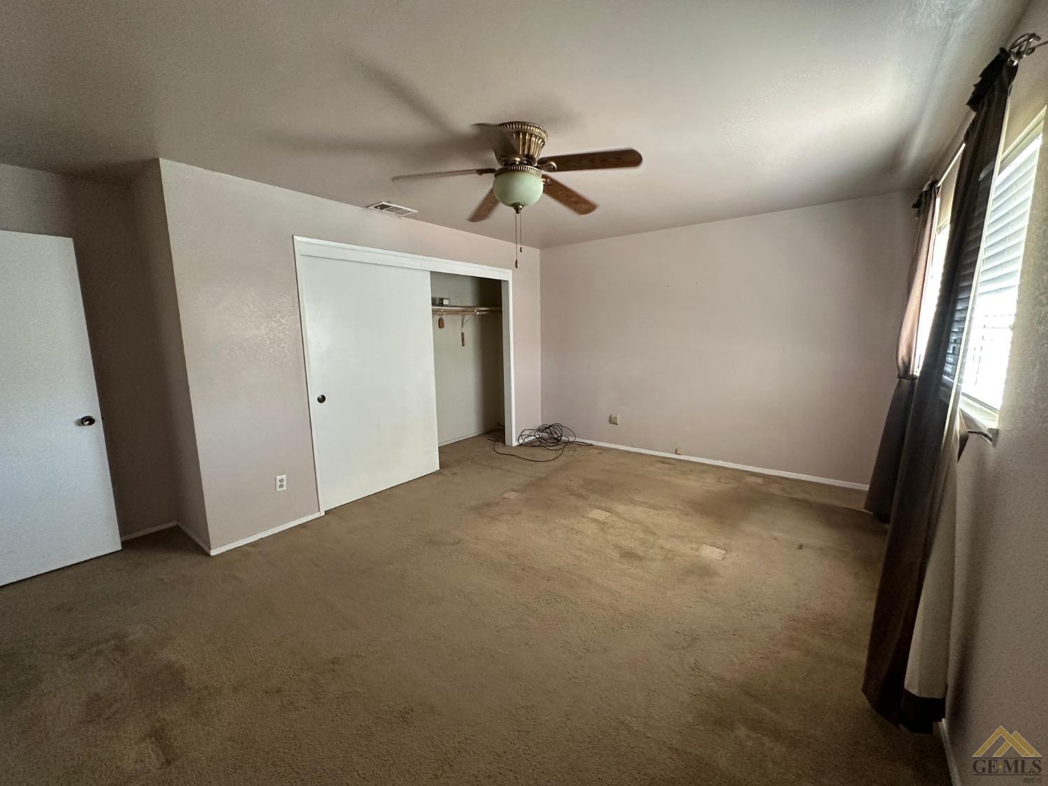 Undisclosed Address Bakersfield, CA 93313 - Photo 18 of 30 en empty room with windows and ceiling fan