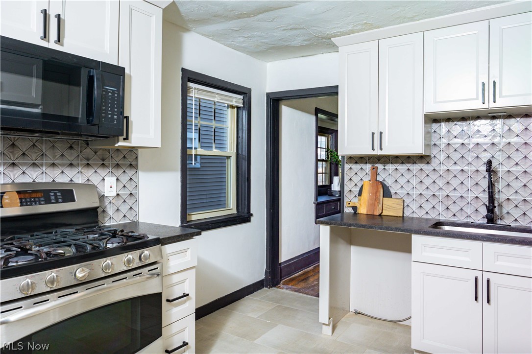 3254 Redwood Road Cleveland Heights, OH 44118 - Photo 15 of 49 Kitchen with sink, light tile floors, tasteful backsplash, stainless steel range with gas cooktop, and white cabinetry