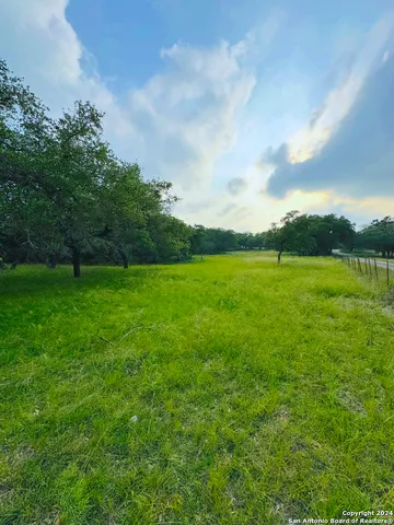 a view of a green field with wooden fence