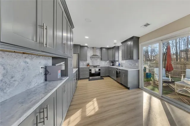 a large kitchen with stainless steel appliances granite countertop a large counter top a stove a sink and a refrigerator