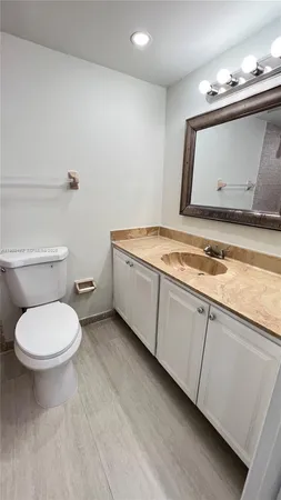 a bathroom with a granite countertop toilet sink and mirror
