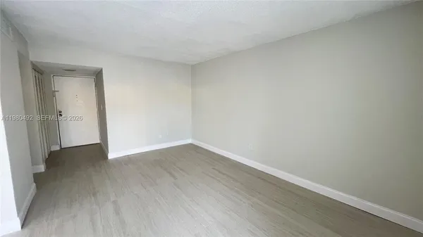 a view of an empty room with wooden floor and closet
