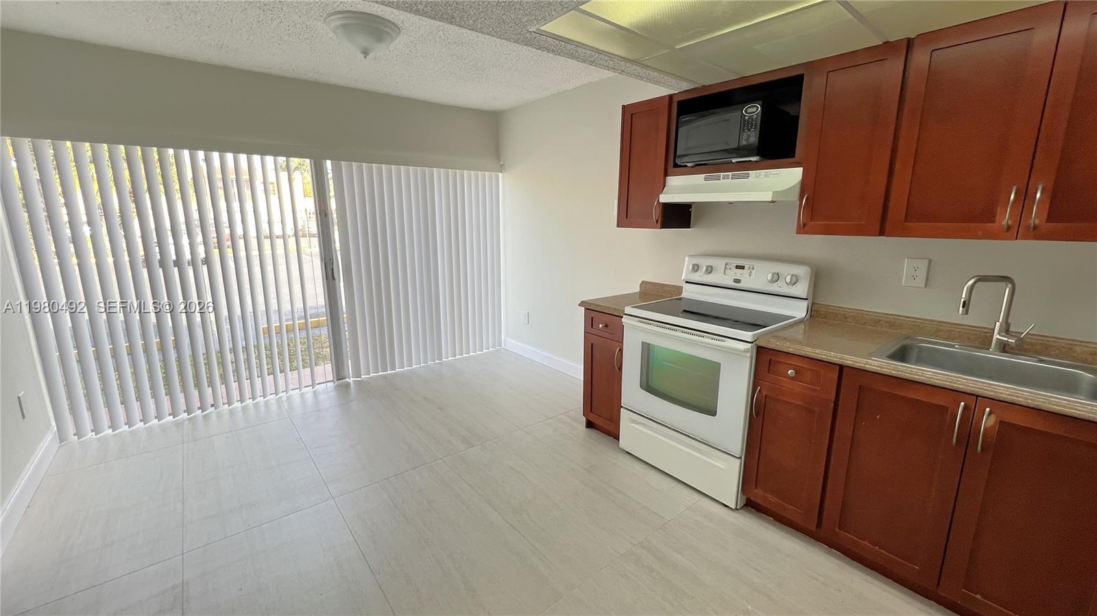 9331 Southwest 4th Street, Unit 101A Miami, FL 33174 - Photo 7 of 15 a kitchen with stainless steel appliances wooden cabinets and a stove top oven