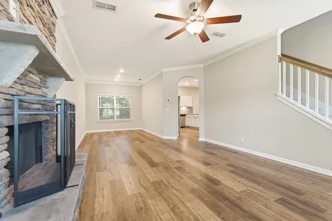 a view of empty room with wooden floor and fan