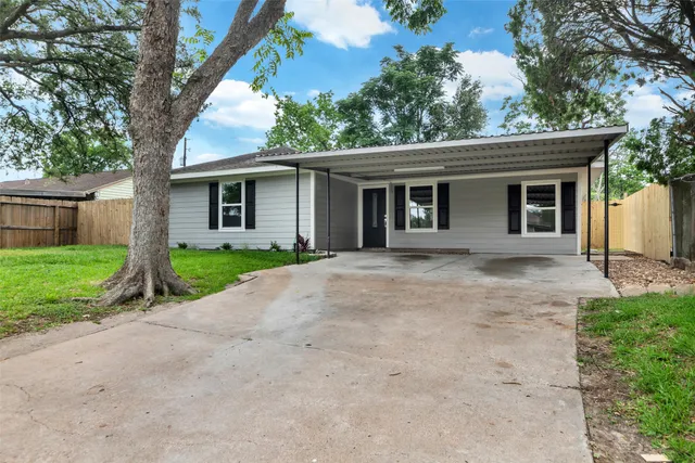 a view of a house with a yard and large tree
