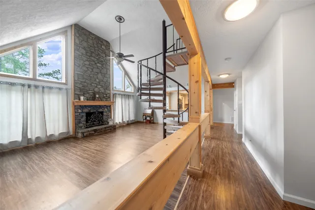 a view of a living room with wooden floor and a fireplace