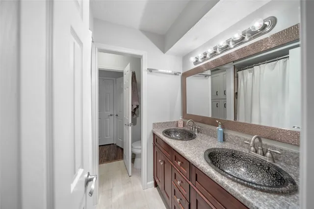 a bathroom with a granite countertop double vanity sink and a mirror