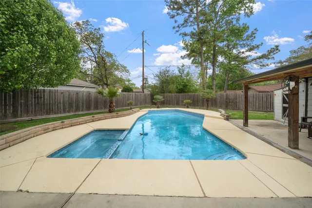 a view of backyard with swimming pool and seating space