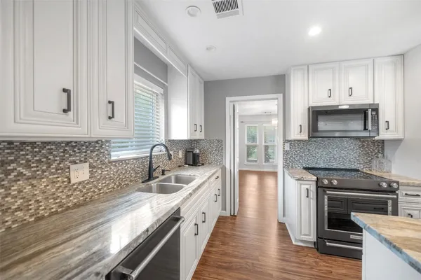 a kitchen with granite countertop white cabinets and stainless steel appliances