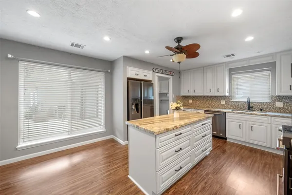 a kitchen with granite countertop a stove a sink and wooden floors