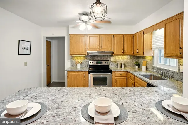 a kitchen with stainless steel appliances granite countertop a stove a sink a refrigerator wooden floor and a dining table with wooden floor