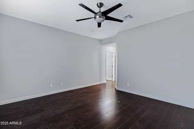 an empty room with wooden floor and a ceiling fan